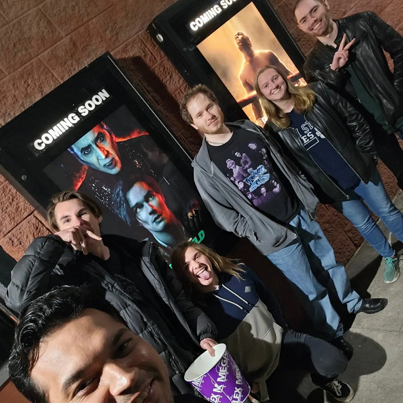 Film club posing outside a theater with movie posters
