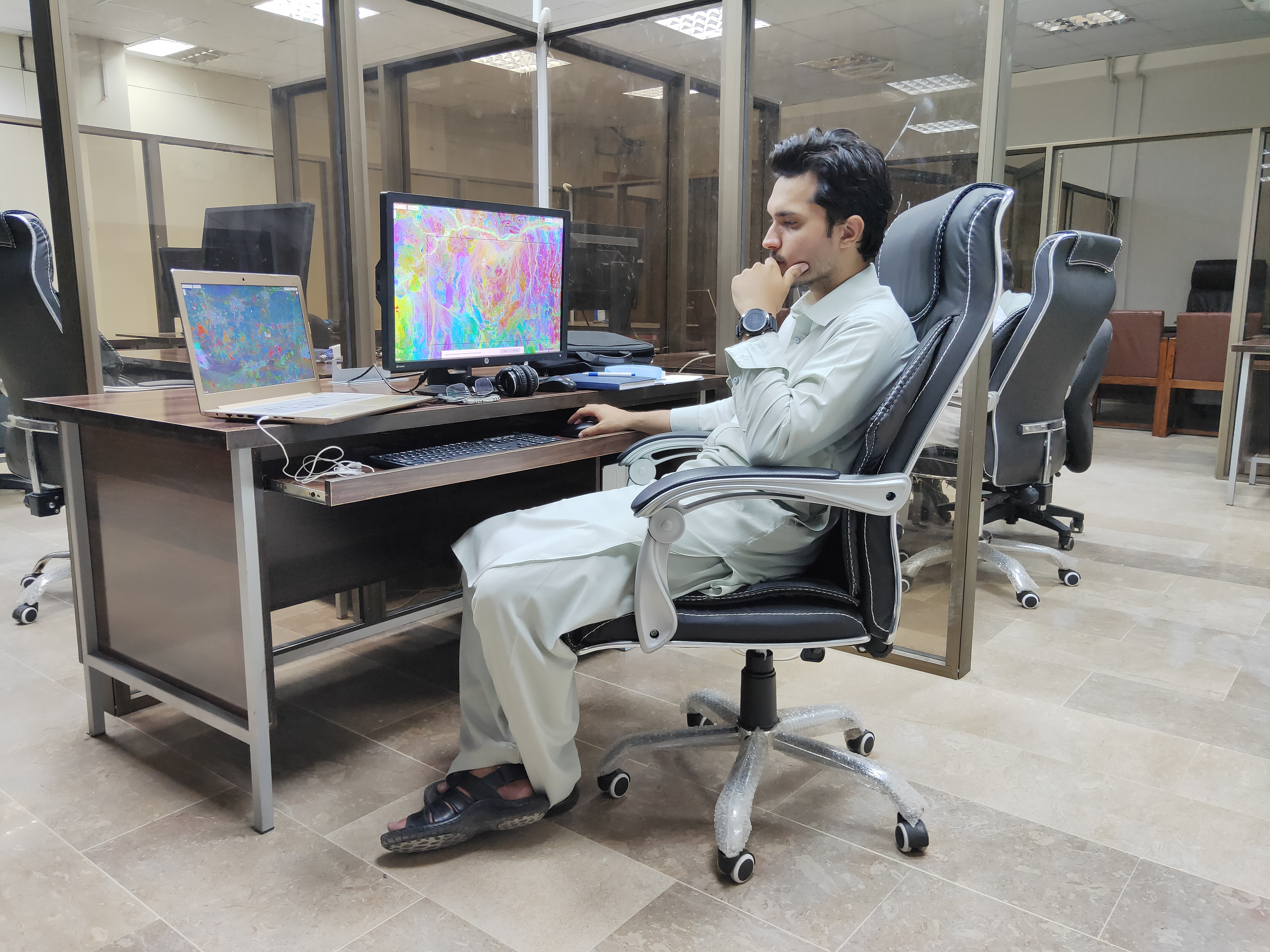 Fawad working at a computer analyzing colorful remote sensing data
